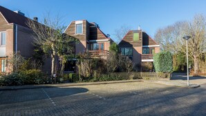 Eine Wohnstraße mit zwei Häusern, eines davon mit Schornstein, das andere mit Balkon.
