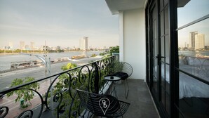 A balcony with a view of a river and cityscape, featuring a table and chairs. - 96 Riverfront Apartment (Đà Nẵng)