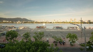 A waterfront parking area with boats, a clear sky, and distant cityscape. - 96 Riverfront Apartment (Đà Nẵng)