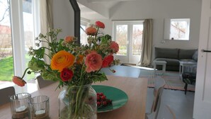 A room with a wooden table, a vase of flowers, and a green plate with berries.