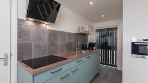 Una cucina moderna con una TV a schermo piatto, piastrelle grigie, un piano di lavoro in legno e un forno integrato.