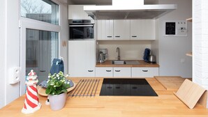 Une cuisine moderne avec des meubles blancs, une cuisinière noire et une machine à café.