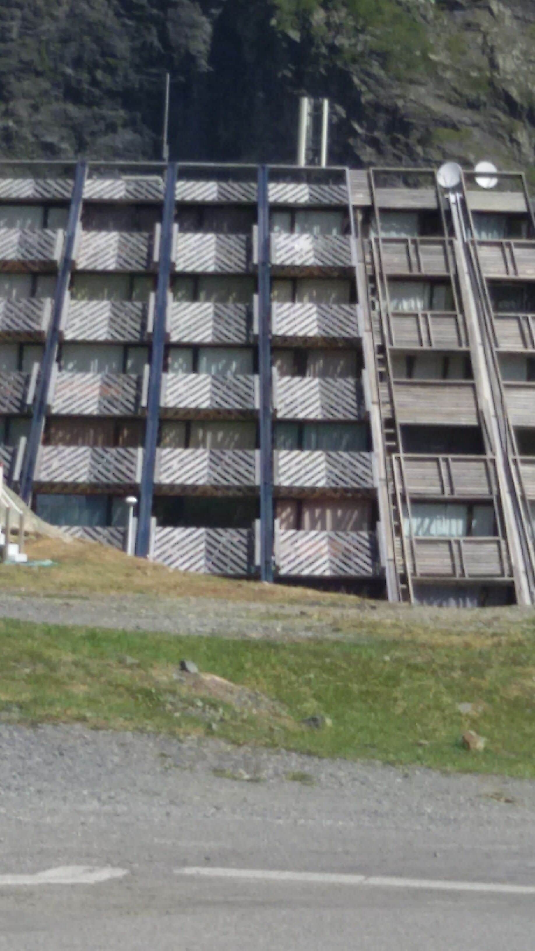 A multi-story building with a distinctive chevron-patterned facade, featuring balconies and a central stairwell.