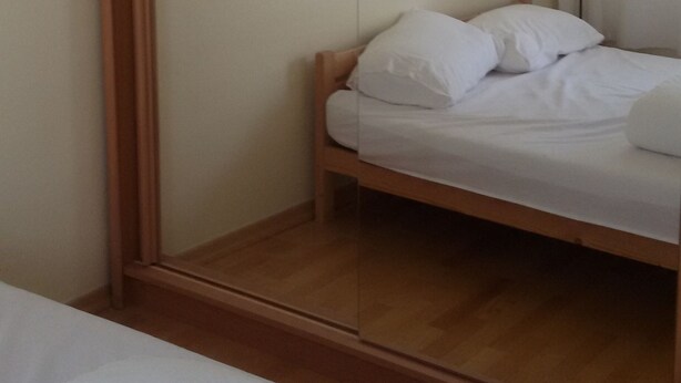 Une chambre à coucher avec un lit, une armoire en bois et un miroir.