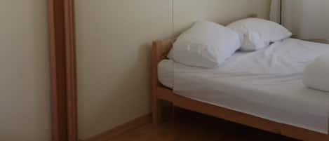 A bedroom with a bed, a wooden wardrobe, and a mirror.