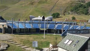 Une centrale solaire composée de rangées de panneaux solaires, d’une aire de stationnement et d’un bâtiment doté d’un toit végétalisé.