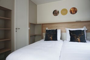 A hotel room with a large bed, two pillows with deer designs, a wooden headboard, and a wall with three circular decorations. - 28-person Group Villa (Voorthuizen)