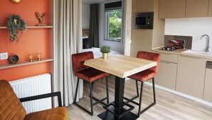Una cocina moderna con una mesa de madera y sillas rojas, un microondas y un lavamanos.