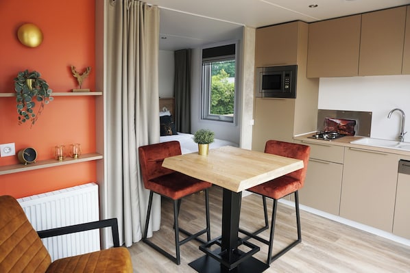 A modern kitchen with a wooden table and red chairs, a microwave, and a sink. - 28-person Group Villa (Voorthuizen)