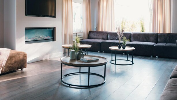 Una sala de estar moderna con un sofá, dos mesas auxiliares, un televisor de pantalla plana y una chimenea.