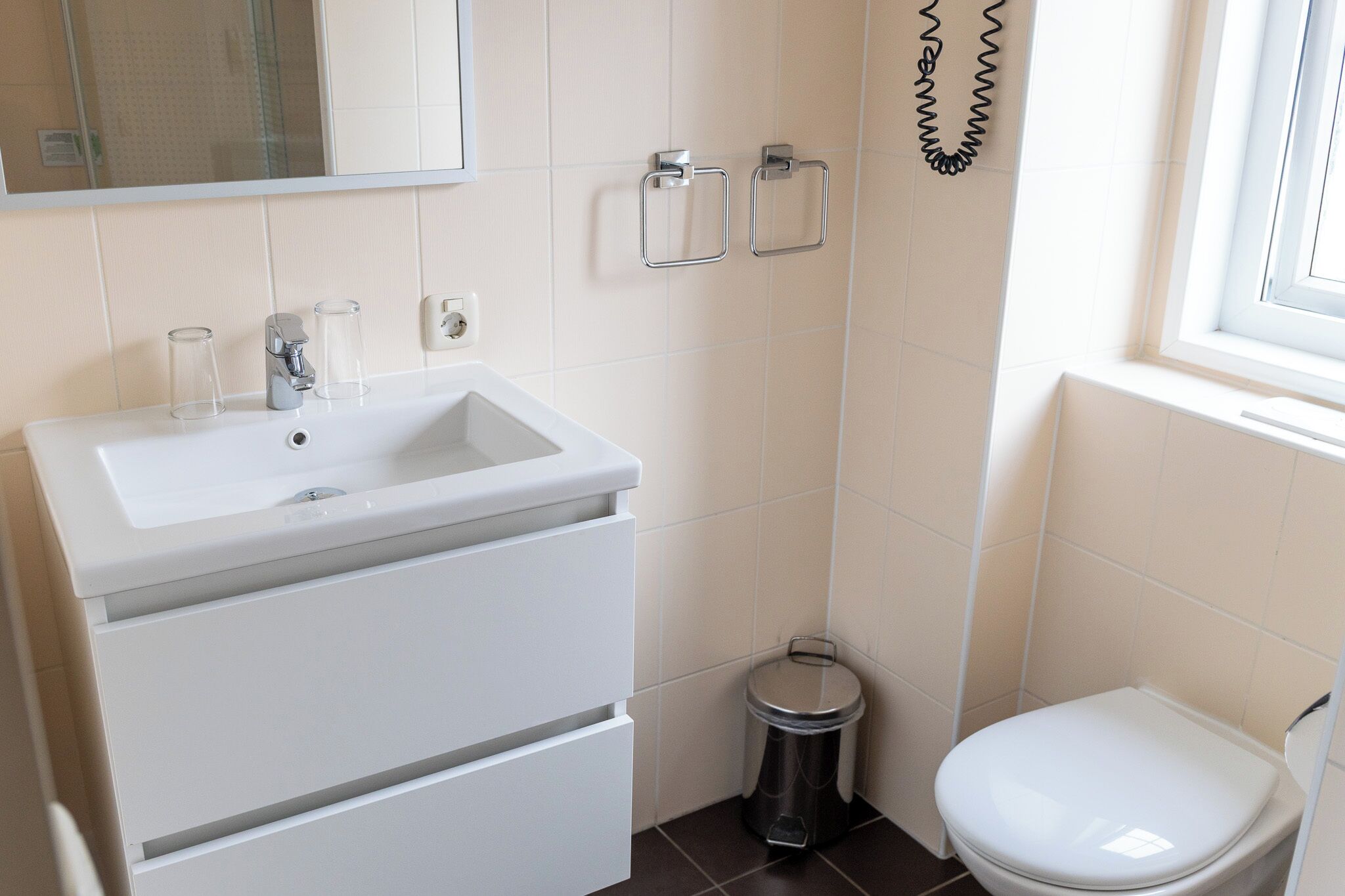 Une salle de bain avec un lavabo blanc, un miroir et des toilettes.
