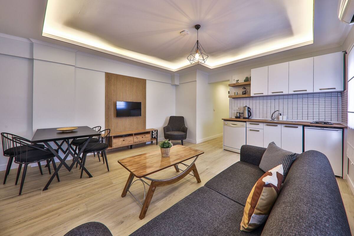 A modern living room with a dining table, sofa, and kitchen area.