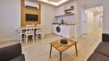 A compact living space with a dining area, a washing machine, and a kitchenette.