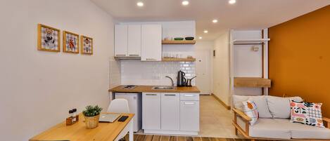 A compact living space with a kitchenette, a dining area, and a sofa.