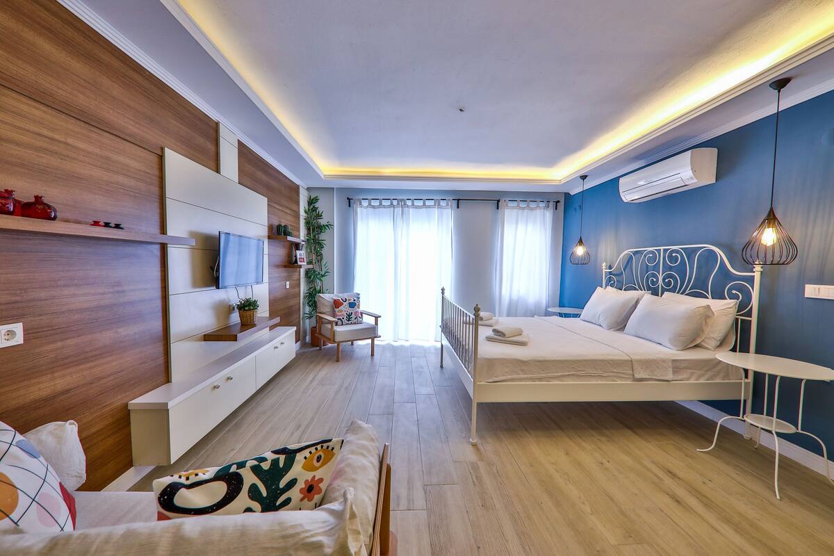 A modern bedroom with a bed, bedside table, and a TV on a wooden wall.