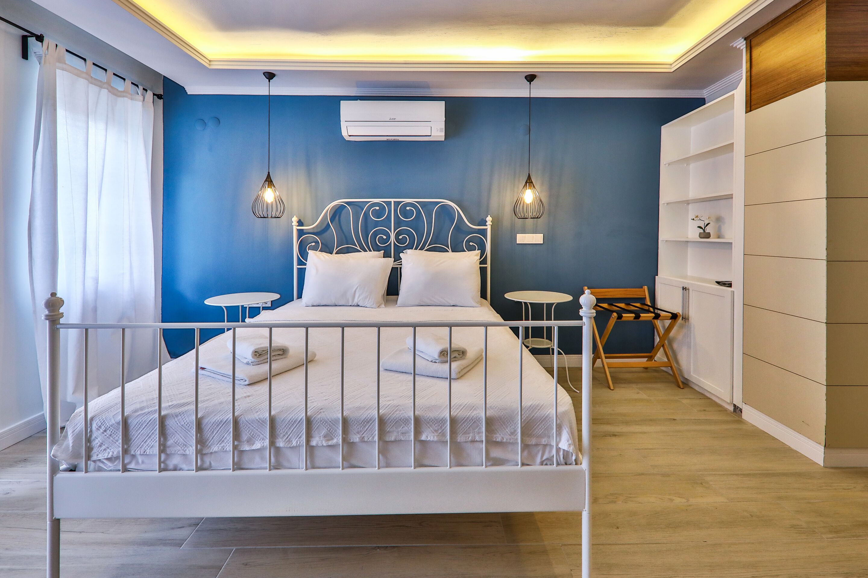 A neatly arranged bedroom with a bed, bedside tables, and a wardrobe.