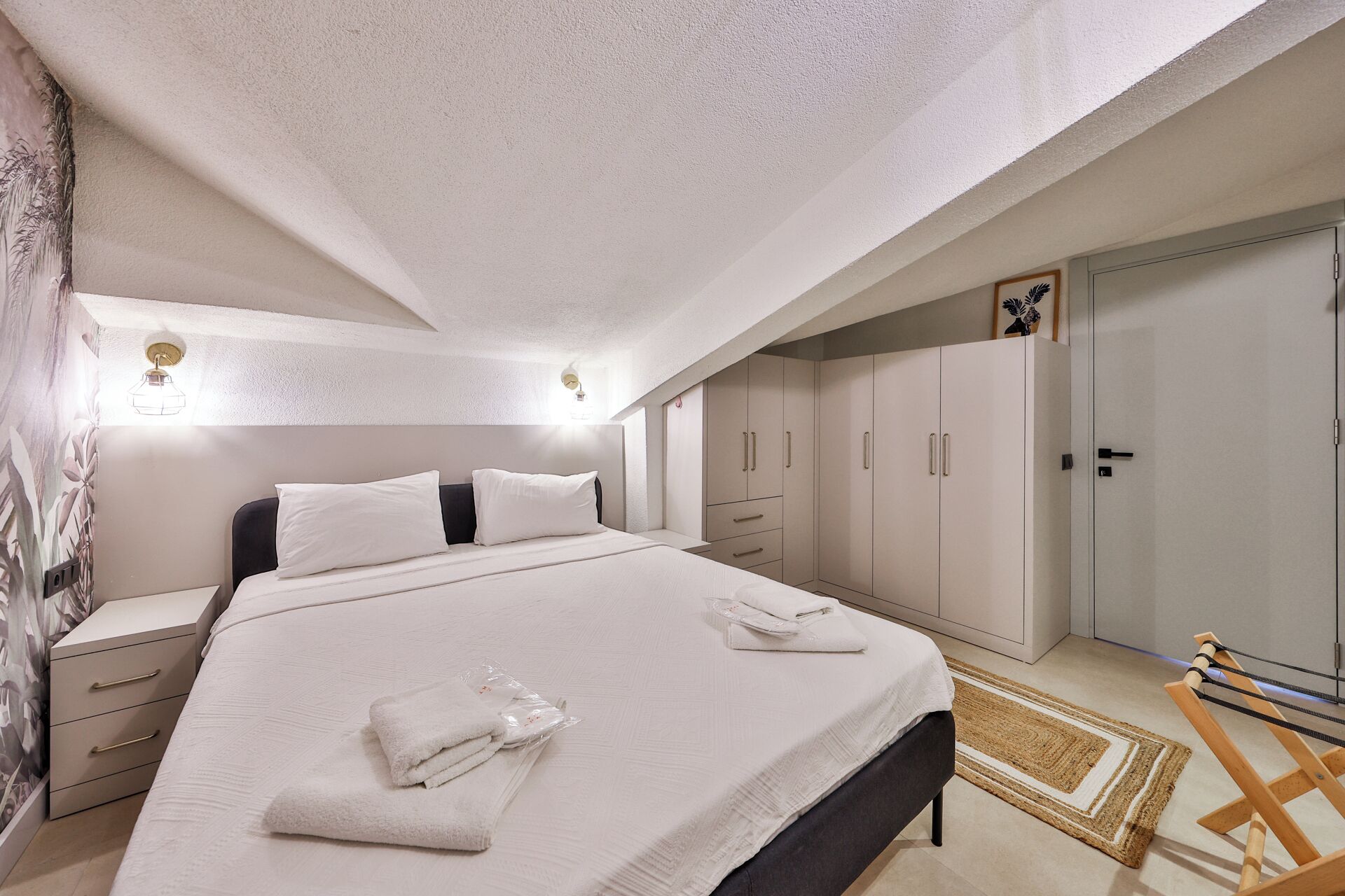 A bedroom with a bed, bedside tables, a wardrobe, and a bench.