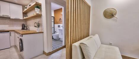 A modern kitchen with white cabinets, a wooden countertop, and a built-in washing machine.