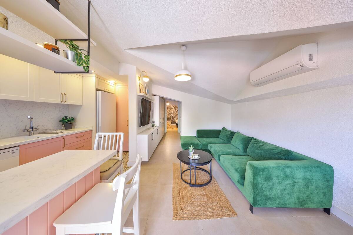 A compact living space with a kitchenette, a green sofa, and a dining area.