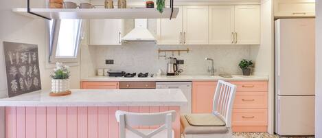 A modern kitchen with white cabinets, a central island, and a refrigerator.