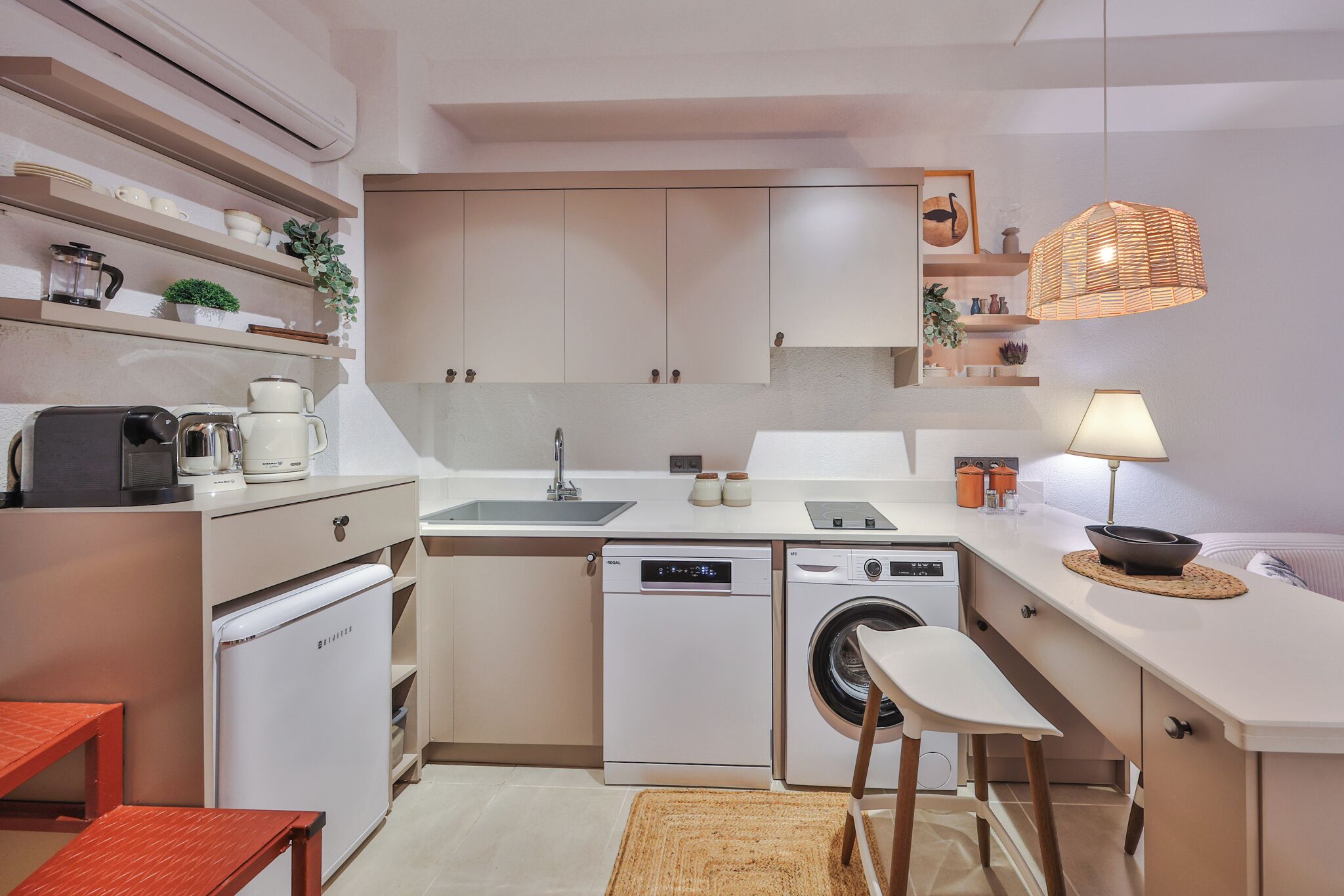 A compact kitchen with a dishwasher, washing machine, and a small dining area with a table and chairs.