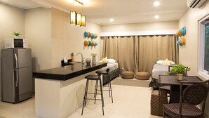 Una cocina compacta con refrigerador, microondas y taburetes de bar.