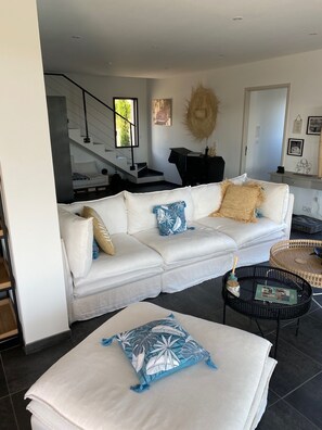 Uma sala de estar moderna com um sofá branco modular, uma mesa de centro e uma almofada decorativa estampada.