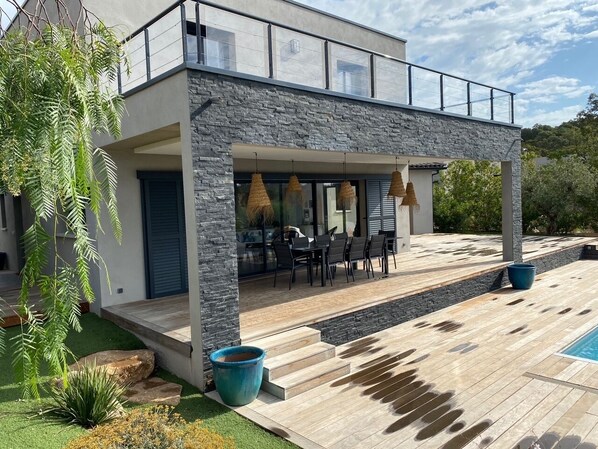 Uma casa moderna com fachada de pedra, piscina e mobiliário para área externa.