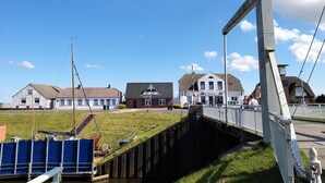 A bridge with a pedestrian walkway, a grassy area, and buildings with traditional architecture.