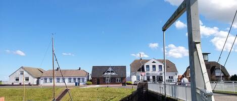 A bridge with a pedestrian walkway, a grassy area, and buildings with traditional architecture.