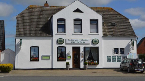 A white building with a sign reading "Restaurant - Pension Zur Brücke".
