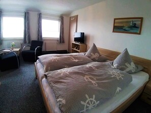 Habitación de hotel con dos camas, un escritorio, una silla, un televisor y un cuadro en la pared.