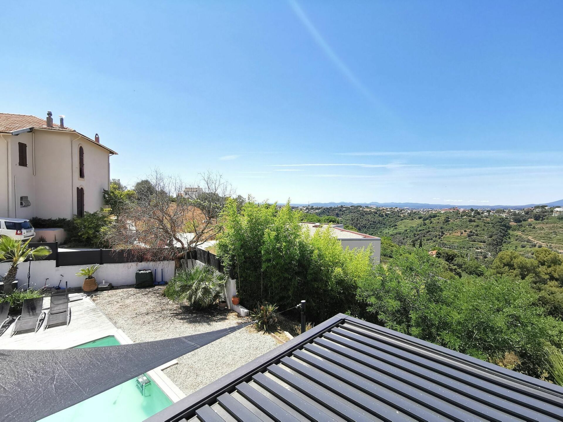 A residential area with a white building, a swimming pool, and a view of a hilly landscape.