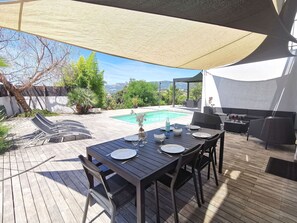 Una terrazza esterna con piscina, tavolo da pranzo e zona relax.