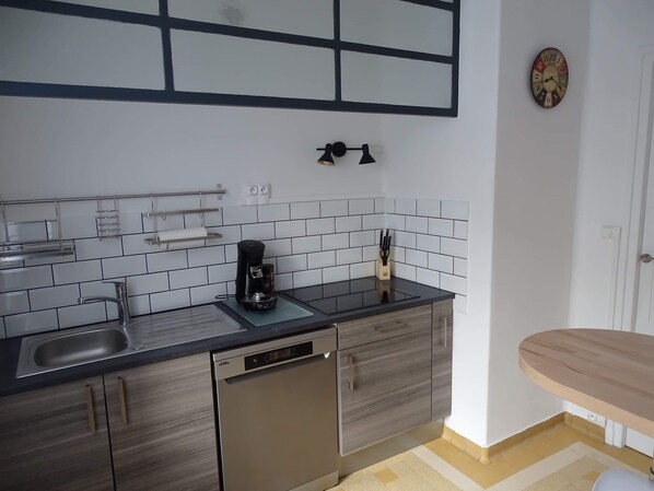 Cocina moderna con lavavajillas, cafetera y bloque de cuchillos en la encimera.