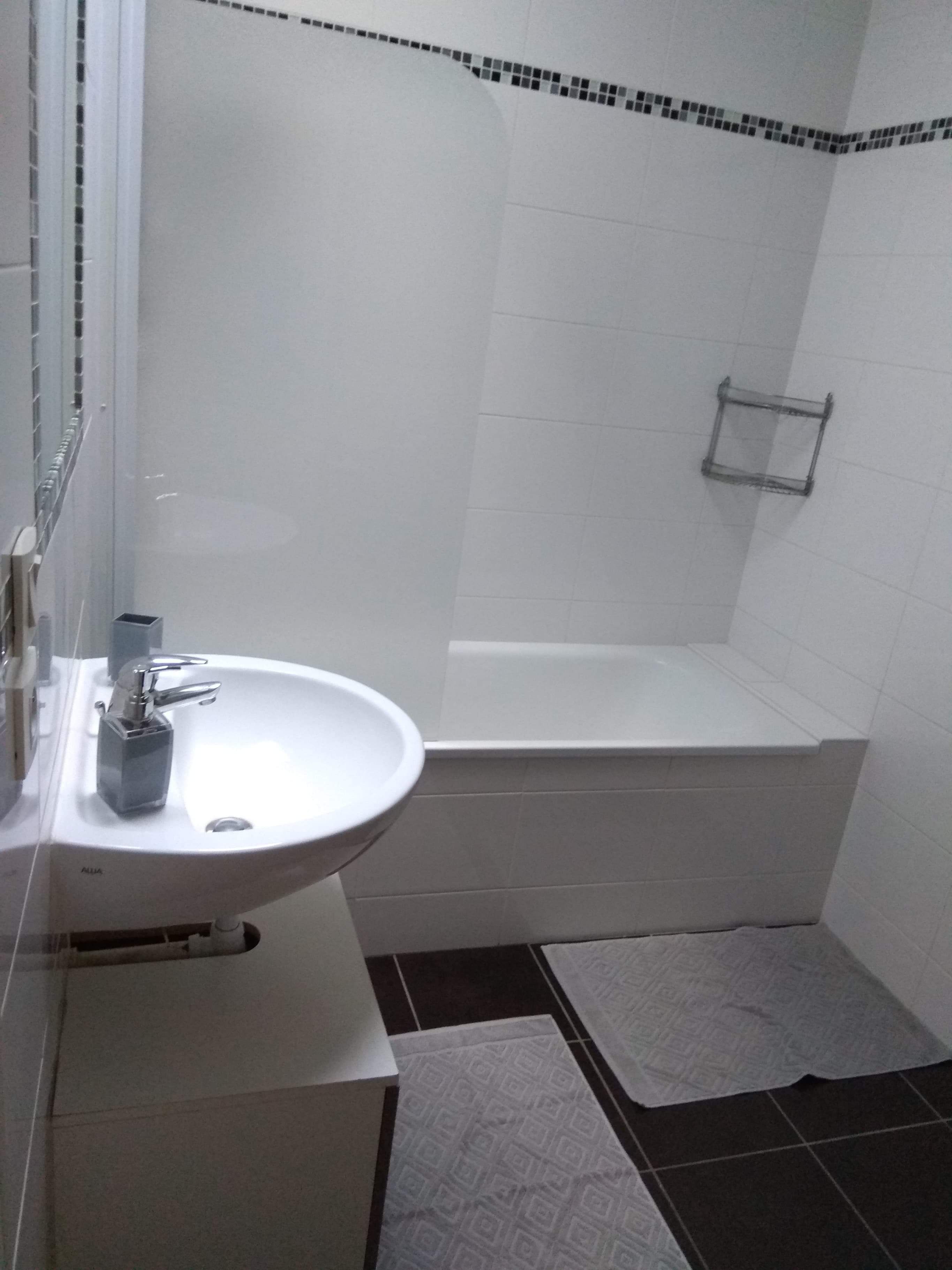 Un baño con lavamanos blanco, bañera y zona de ducha.