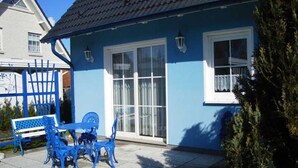 A blue house with a patio, a table with chairs, and a bench. - Friesenhus - Ferienwohnung (Kühlungsborn)