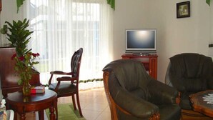 A living room with a television, two leather chairs, a wooden coffee table, and a green plant on a side table. - Friesenhus - Ferienwohnung (Kühlungsborn)