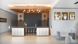 A modern reception area with a marble counter, a wooden ceiling, and framed artwork on the wall. - Beach Walk Hotel (Dubai)