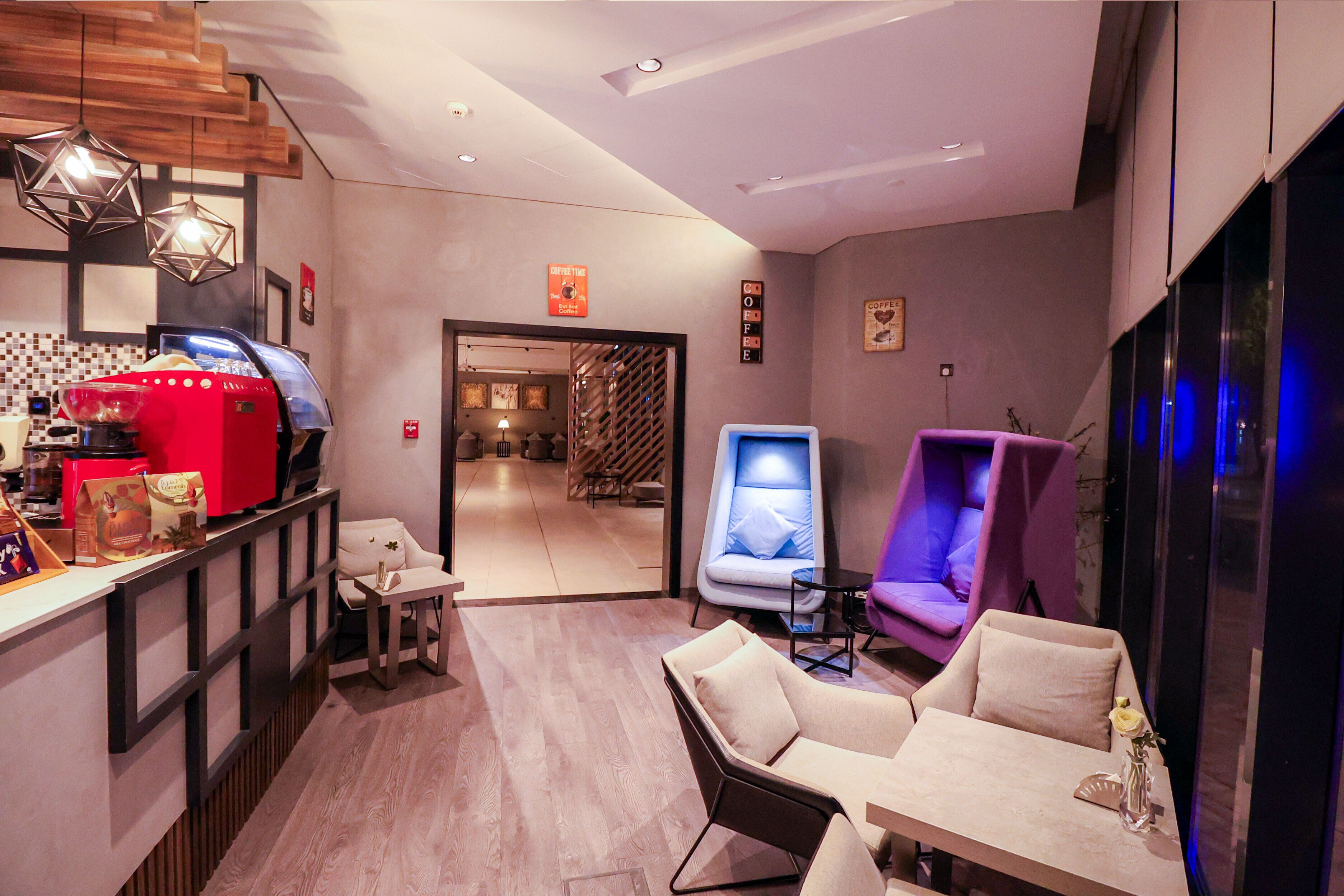 A modern room with a coffee machine, seating area, and a massage chair.