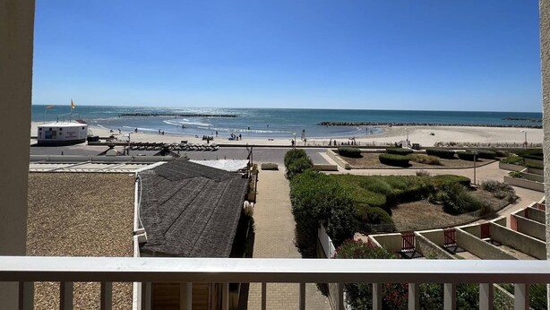 A beachfront view from a balcony, including a lifeguard tower, beach, and clear blue sky.