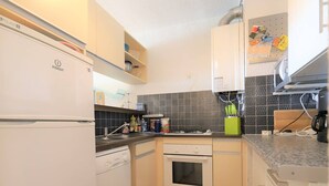 A compact kitchen with a refrigerator, oven, sink, and a tiled backsplash.