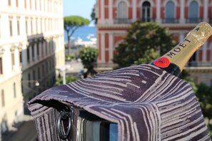 En flaska Moët-champagne med ett mönstrat tygöverdrag, placerad mot en stadsbild med historiska byggnader.