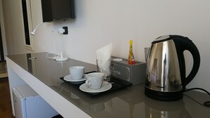 A modern kitchen counter with a kettle, two cups, a tissue box, and a small bottle. - Suite Napoli Riviera (Naples)