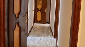 A hallway with wooden doors and a marble floor. - Suite Napoli Riviera (Naples)
