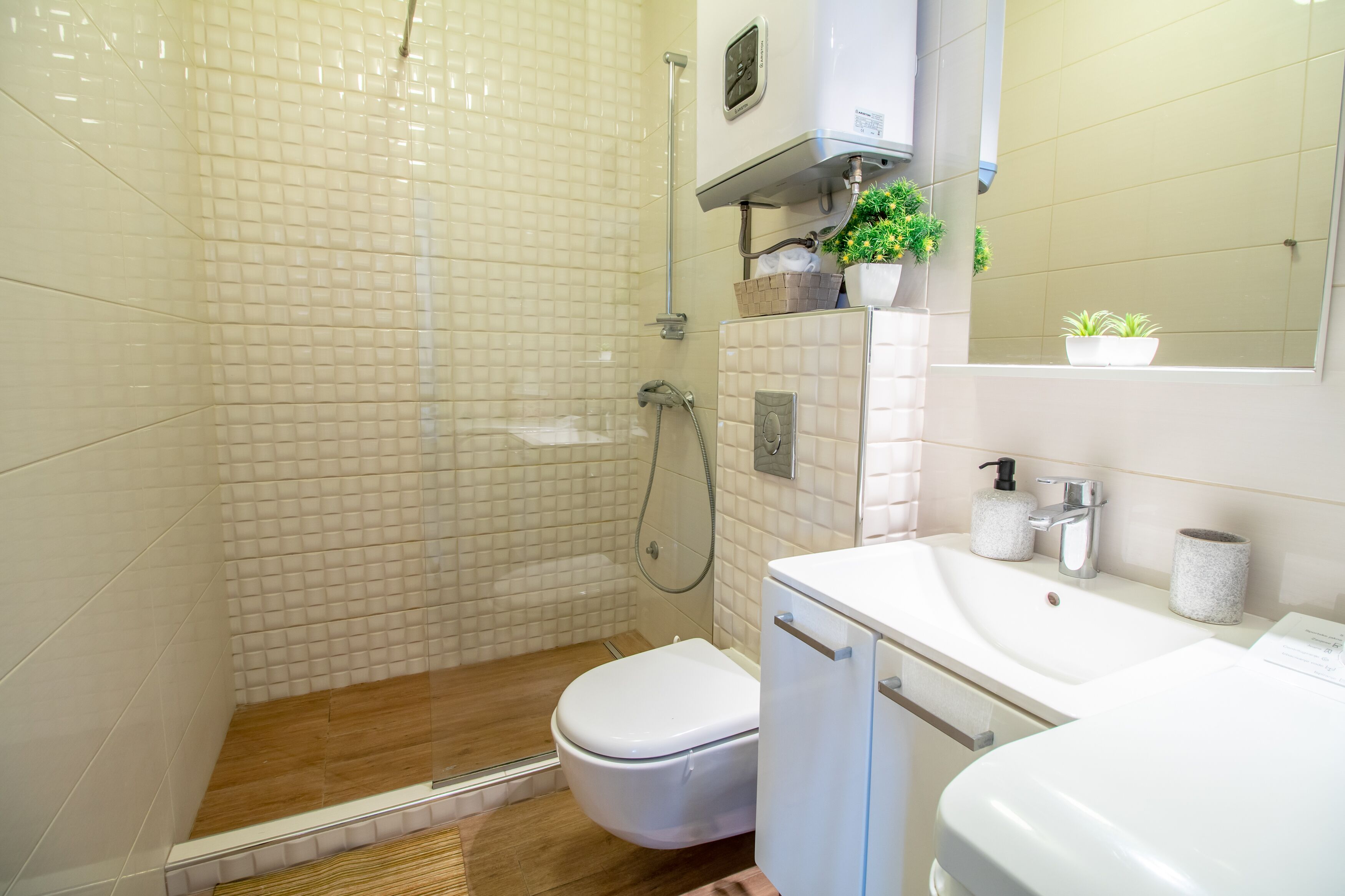 Un baño moderno con ducha, inodoro, lavamanos y una planta en maceta.