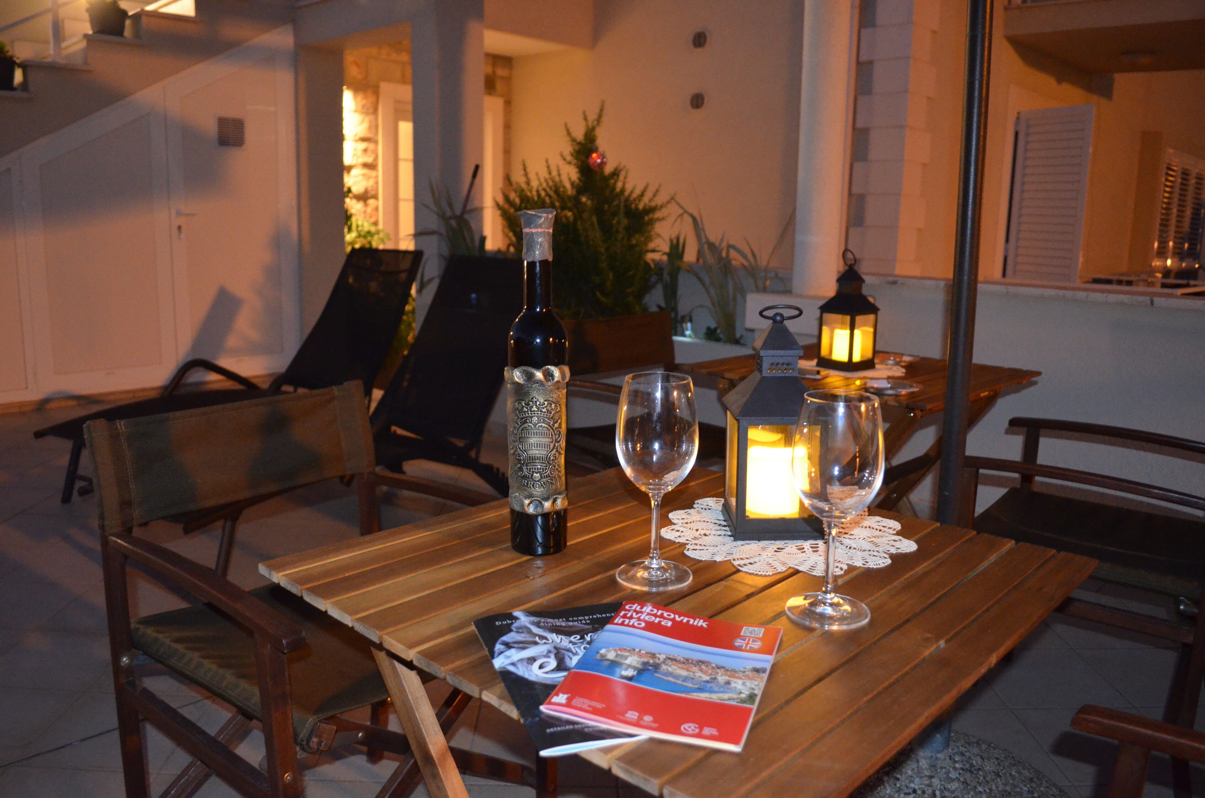Uma mesa de madeira com uma garrafa, dois copos, uma vela e uma revista.