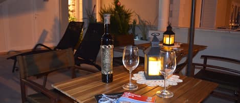 Uma mesa de madeira com uma garrafa, dois copos, uma vela e uma revista.
