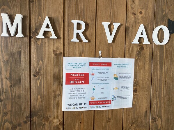 Una superficie de madera con letras que deletrean 'MARVAO' y un folleto con pautas sobre COVID-19.