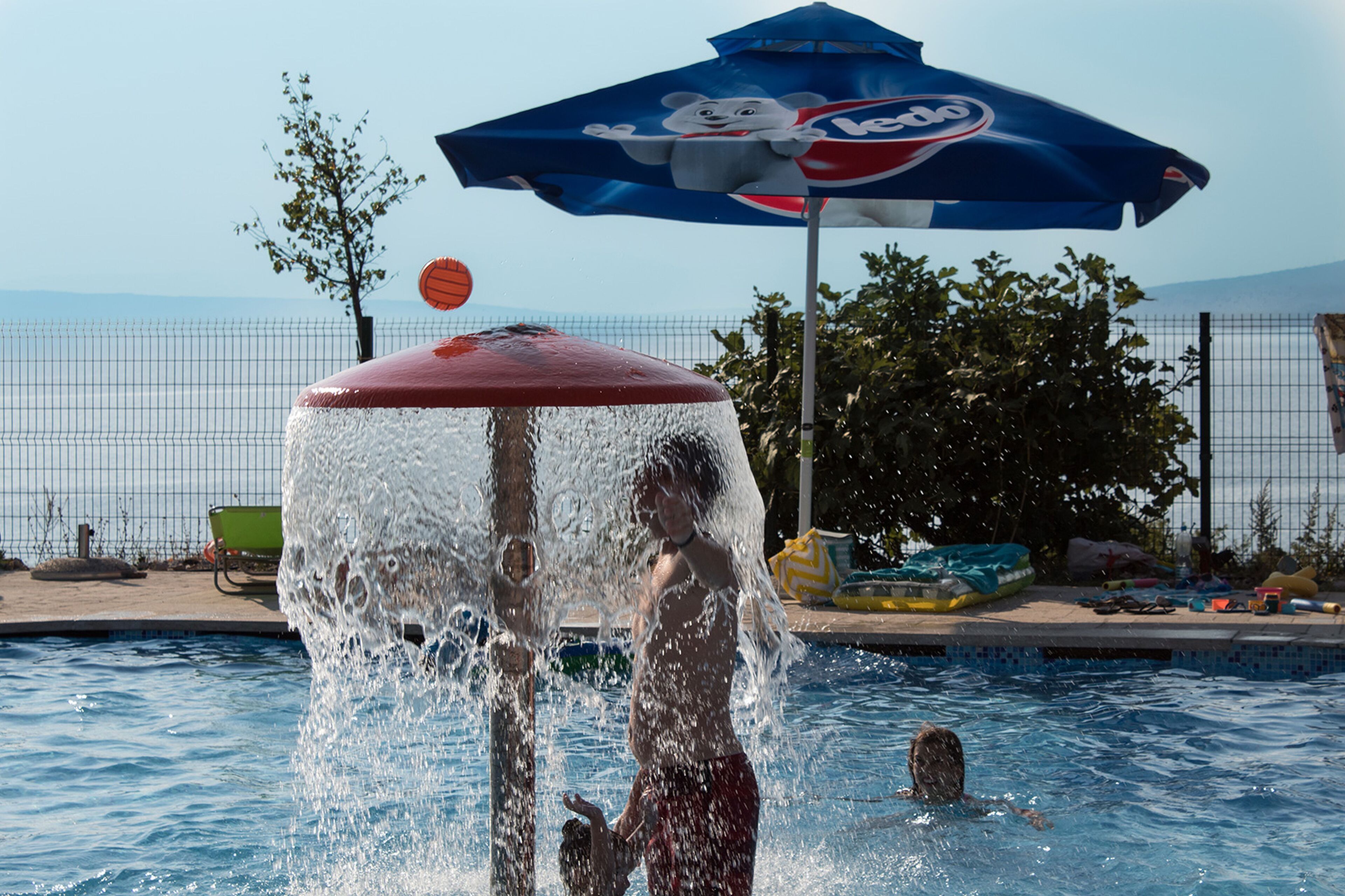 A swimming pool with a water fountain and a children's play area.